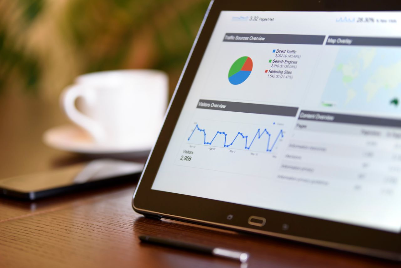 Crafting Captivating Headlines: Your awesome post title goes here Close-up of a tablet displaying analytics charts on a wooden office desk, alongside a smartphone and coffee cup.